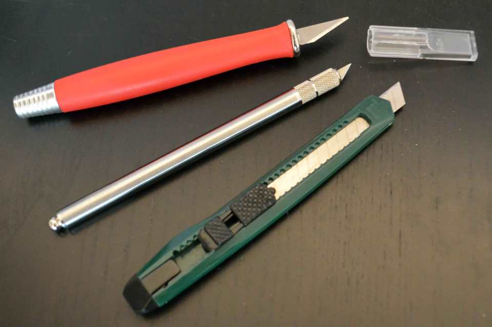 Zwei Skalpelle (oben) in unterschiedlichen Größen für die Feinarbeit und ein einfacher Cutter (unten) für größere, gerade Schnitte.